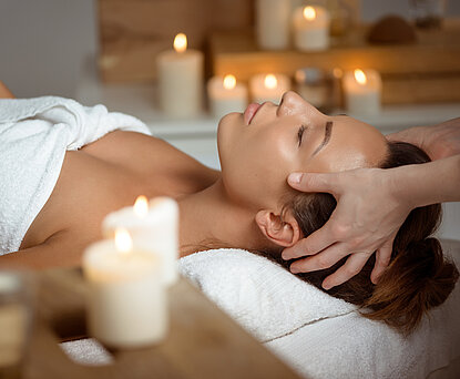 Young beautiful brunette girl having face massage relaxing in spa salon. Eyes closed. Copy space.