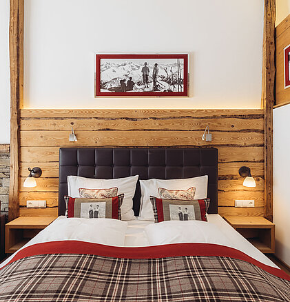 Doppelbett in der Suite Brunella im Genusshotel Vermala mit gepolstertem Kopfteil, Holzelementen und alpinem Design.