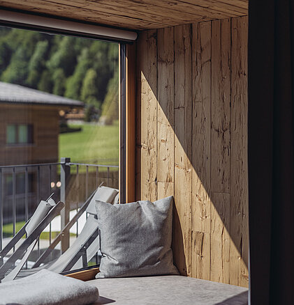 Gemütliche Liegefläche im Zimmer Heimatblick des Genusshotel Vermala mit Holznische, Balkonblick und alpinem Ambiente.