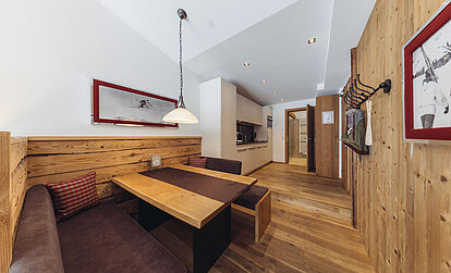Essbereich der Suite Alpenrose im Genusshotel Vermala mit Eckbank, Holztisch, Pendelleuchte und alpiner Einrichtung.