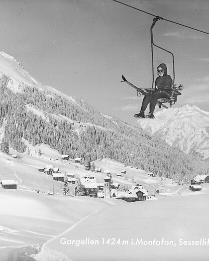 Historische Winteraufnahme des Sessellifts in Gargellen im Montafon mit Skifahrer, Schneelandschaft und Bergpanorama.