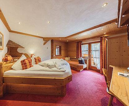 Doppelzimmer Heimatliebe Komfort im Genusshotel Vermala in St. Gallenkirch mit Doppelbett, Holzinterieur und gemütlichem Sitzbereich.