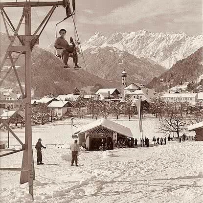 Historische Winteraufnahme des Kapell Sessellifts im Montafon mit Skifahrern, Liftanlage und verschneiter Bergkulisse.