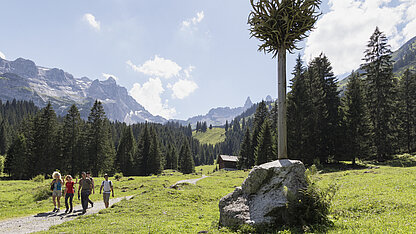 Geweihbaum bei der Gauertaler AlpkulTour im Montafon mit Wanderern, Kunstinstallation und Blick auf die Drei Türme.
