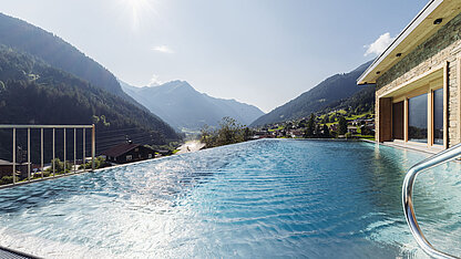 Panoramapool im Genusshotel Vermala mit Blick auf die Montafoner Bergwelt und sonniger Wellnessatmosphäre.