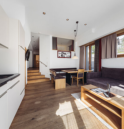 Familiensuite Edelweiß im Genusshotel Vermala mit Wohnzimmer, Küchenzeile, Esstisch, Sofa und hellem Wohnbereich.