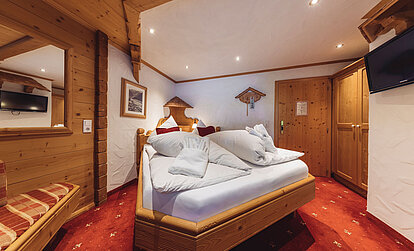Alpines Zimmer Heimatnest im Genusshotel Vermala mit Doppelbett, Holzvertäfelung und traditioneller Einrichtung.