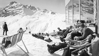 Historische Aufnahme vom Restaurant Versettla im Jahr 1969 mit Gästen auf der Sonnenterrasse und Blick auf die verschneite Bergwelt im Montafon.