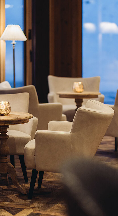 Herzstück Hotelbar im Genusshotel Vermala mit Lounge-Sesseln, kleinen Tischen und Blick auf St. Gallenkirch im Montafon.